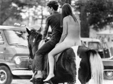 A Naked Young Women and Escort Ride a Horse Through Goose Lake Park at 3 Day Rock Music Festival