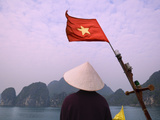 Girl with Conical Hat on a Junk Boat with National Flag and Karst Islands in Halong Bay  Vietnam