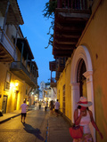 People Stroll Through an Illuminated Narrow Street at Dusk