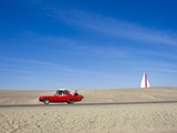 A Red Car Packed Full Lof Luggage Traveling on a Desolate Road
