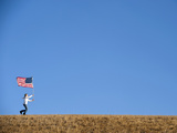 A Teenage Girl Runs across a Field with an American Flag