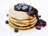A Pile of Pancakes with Blueberry Sauce and Maple Syrup