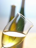 Glass of White Wine  Held at an Angle  in Front of Two Bottles