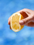 A Hand Squeezing a Lemon