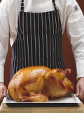Chef Holding Stuffed Roast Turkey on Baking Tray