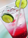 A Glass of Raspberry Soda with Ice Cubes and Lime Slices