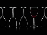 Row of Wine Glasses and a Glass of Red Wine Against a Black Background