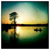 A Couple Paddles a Canoe at Sunset Past Cypress Trees