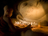 A Novice Monk Lighting Candles at a Massive Buddha Statue in Burma (Myanmar)